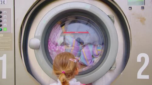 Child Watching Clothes Wash in Laundromat Machine