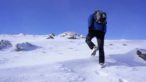 Male hiking on a windy day over snow to the summit of a Mountain at Isle of Skye in Scotland