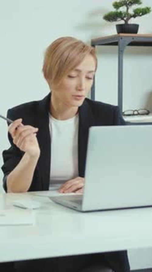 A Woman Types and Takes Notes at Her Desk Demonstrating Productivity