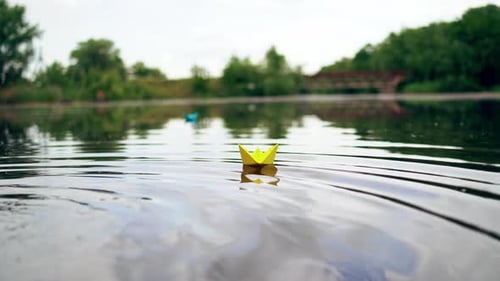 A paper ship floating in the river on the waves. Origami Paper Boat