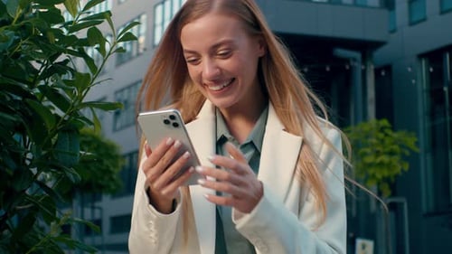 Excited Woman Celebrates Success Looking at Smartphone in City