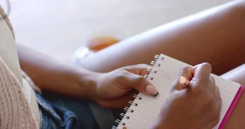 Writing in notepad, woman journaling while relaxing at home with tea
