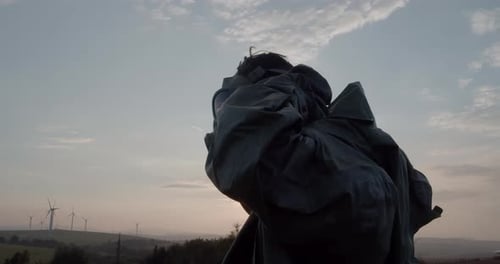 Man in Gas Mask at Sunset by Wind Turbines