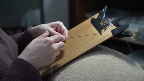 Hands Knotting String on Wooden Clipboard, Indoor