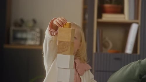 Closeup Child Putting Wooden Block on Top of Tall Tower