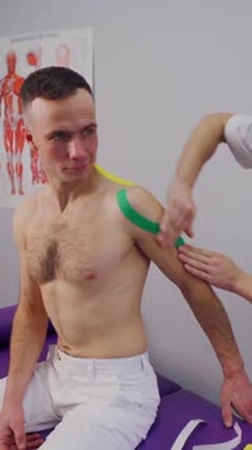 Athletic Tape Applied to Man's Shoulder in Clinic