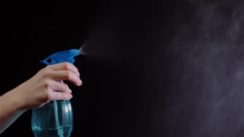 Handsprühflasche mit Nebel vor dunklem Hintergrund