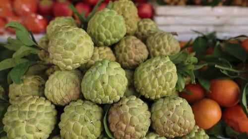 Vietnam Street Market Custard Pile On Crate, Knobbly Green Fruit With Leaves And Orange Accents,
