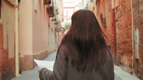 A view from behind of a tourist walking through the narrow streets of an old European city.