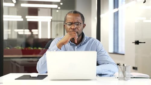 Man Concentrating on Laptop in Bright Office