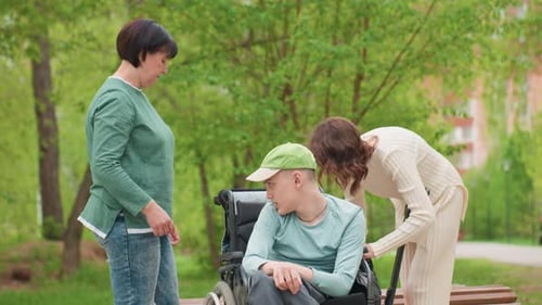 Woman Places Clothes Next To Teen In Wheelchair