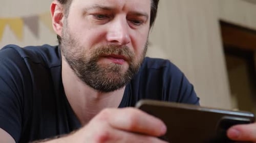 Man Focused on Smartphone Screen Indoors