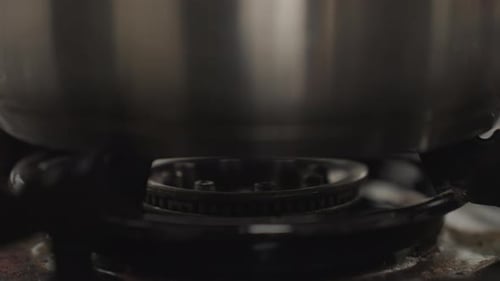 Stainless Steel Pot on Gas Burner with Flame Ignited for Cooking in Kitchen