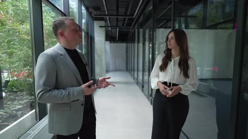 Professional Discussion in Modern Office Corridor Two Business Professionals Engage in Conversation