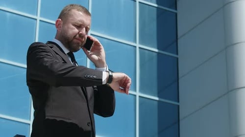 Businessman Professional Caucasian Bearded Man in Suit Having Phone Conversation Looks at the Clock