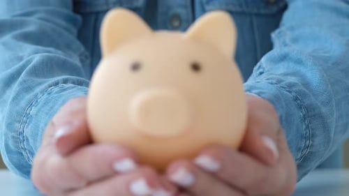 Female Hands Holding Blue Piggy Bank on White Table Saving Money Concept