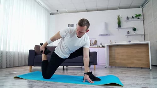 Man Stretching on Yoga Mat in Bright Modern Home