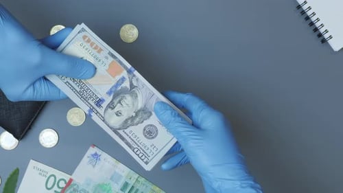 Hands in Gloves Counting Money on Desk