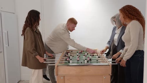 Diverse Coworkers Playing Foosball Together in an Office Breakroom