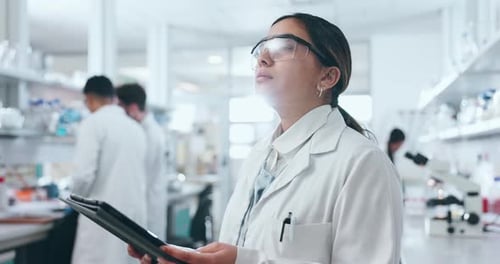 Thoughtful Scientist Using Tablet in Modern Laboratory