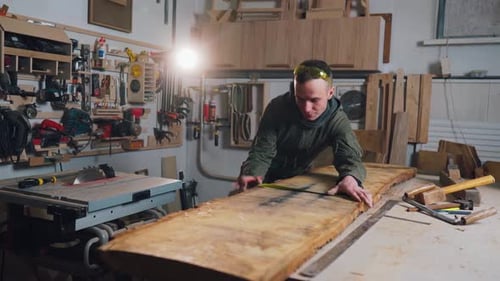 Man Measures and Marks Wood in Workshop