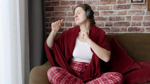 Woman Listens to Music at Home with Headphones