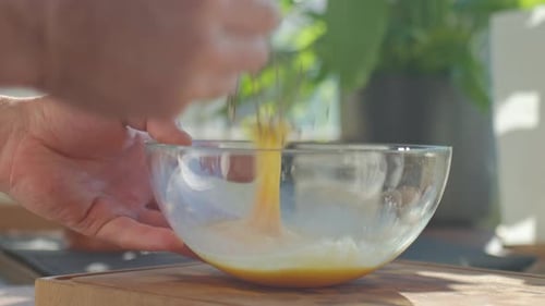 Hands whisking eggs in glass bowl in kitchen