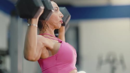 Entschlossene Sportlerin beim Hantelheben im Fitnessstudio