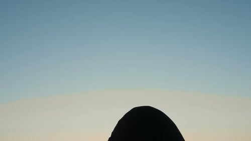 Nachdenklicher junger Mann auf dem Dach bei Sonnenuntergang