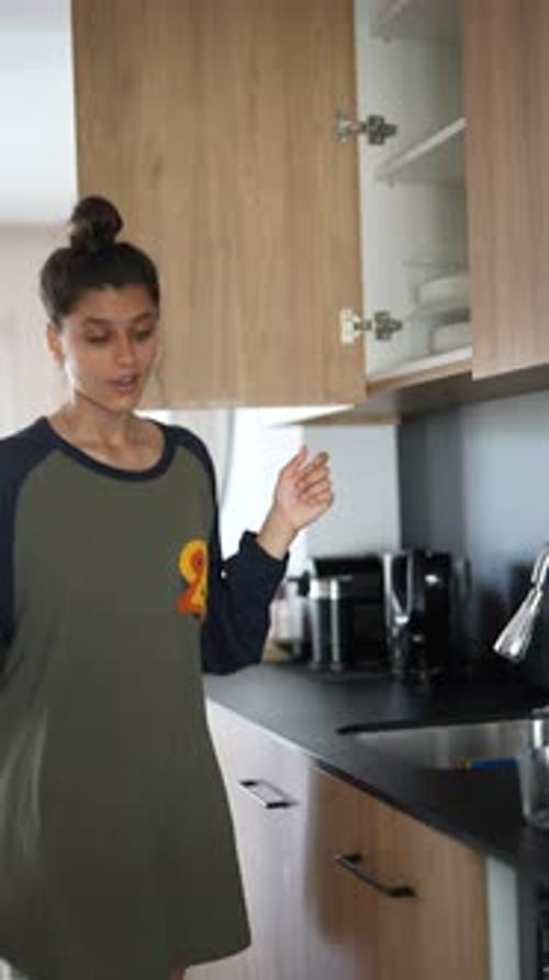 A Woman Reaching for a Cabinet in a Modern Kitchen Engaged in Daily Housework and Household Chores