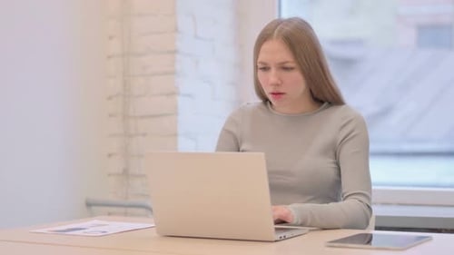 Woman Sneezing While Using Laptop at Desk