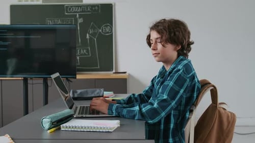 Portrait of Smart Boy Typing on his Laptop During IT Cass in school