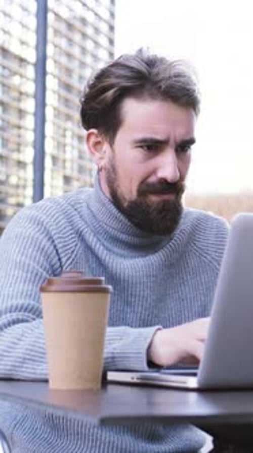 Young Adult Works on Laptop and Drinks Coffee