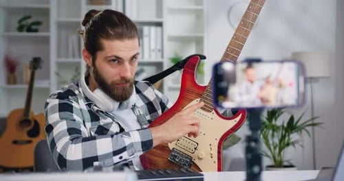 Profesor bloguero caucásico graba un vídeo tutorial de clase para tocar la guitarra eléctrica