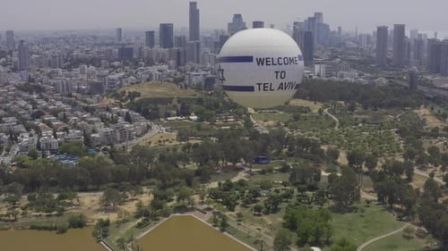 Aerial Shot Of Hot Air Balloon Descending Over Yarkon Park Against Sky In City