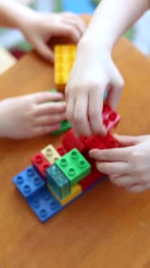 Closeup Hands of Two Kids Hands Building Creative Designs with a Colorful Construction Set