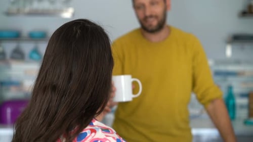 Woman Receives Coffee from Man in Kitchen