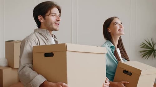Paar bereitet sich auf den Umzug vor, während sie Umzugskartons in der neuen Wohnung tragen