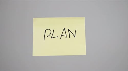 Writing 'Plan' on Sticky Note with Marker