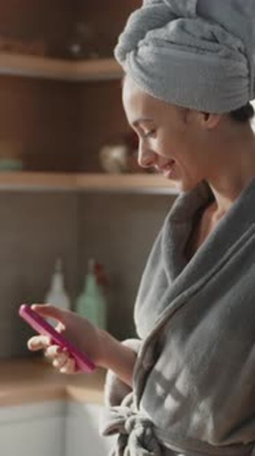 Happy Woman Stand with Towel on Head Use Phone in the Kitchen Stand Texing Smiling After Shower Slow