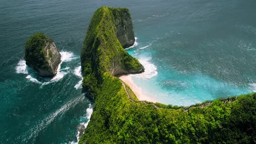 Green rock on the ocean. Mountain rainforest on pristine white sandy beach with azure ocean waves. K