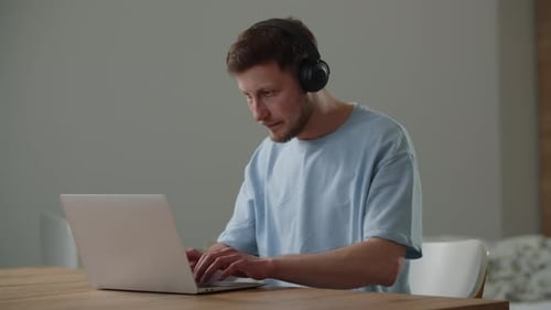 Man with Headphones Using Laptop at Home