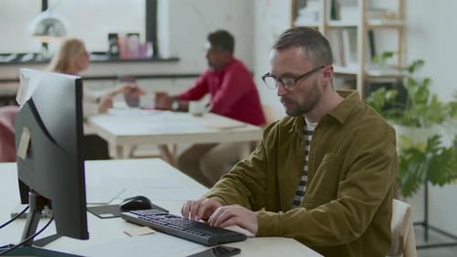Businessman Working on Computer and Writing on Sticky Note at Office Desk