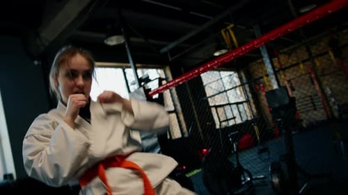 A girl practices karate in a gym A woman in kimono practices movements and poses Martial arts