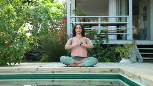 Woman meditating by pool at home, practicing yoga and relaxation outdoors, copy space