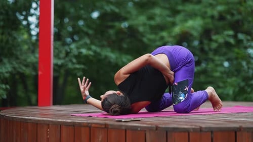 Woman Does Yoga Poses on a Mat Outdoors