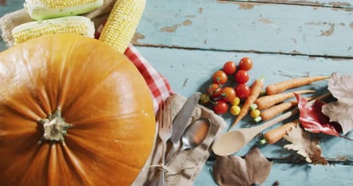 Close up view of pumpkin, multiple food ingredients and cutlery on wooden surface