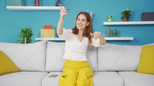 Happy Woman Dances Energetically on Gray Couch