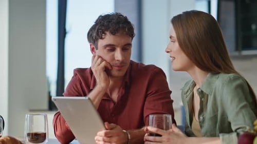 Smiling Couple Using Tablet at Kitchen Table