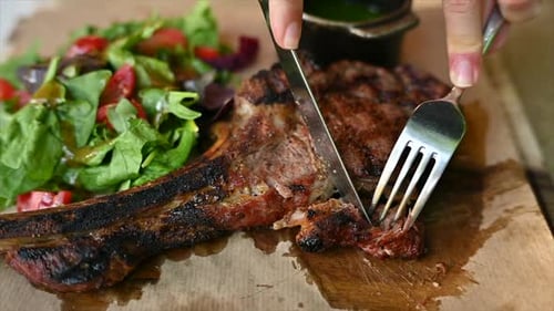 Woman eating beef stake at a restaurant with vegetables